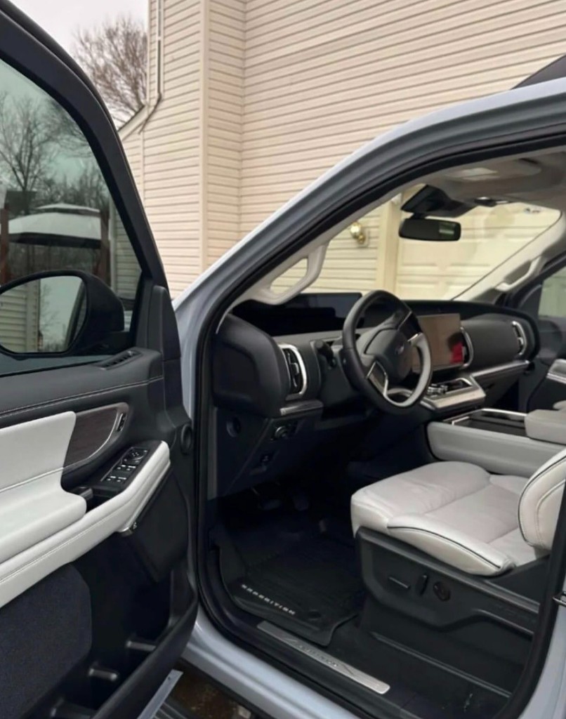 Showroom-clean SUV interior with light leather seats, large displays, and immaculate floor and door panels